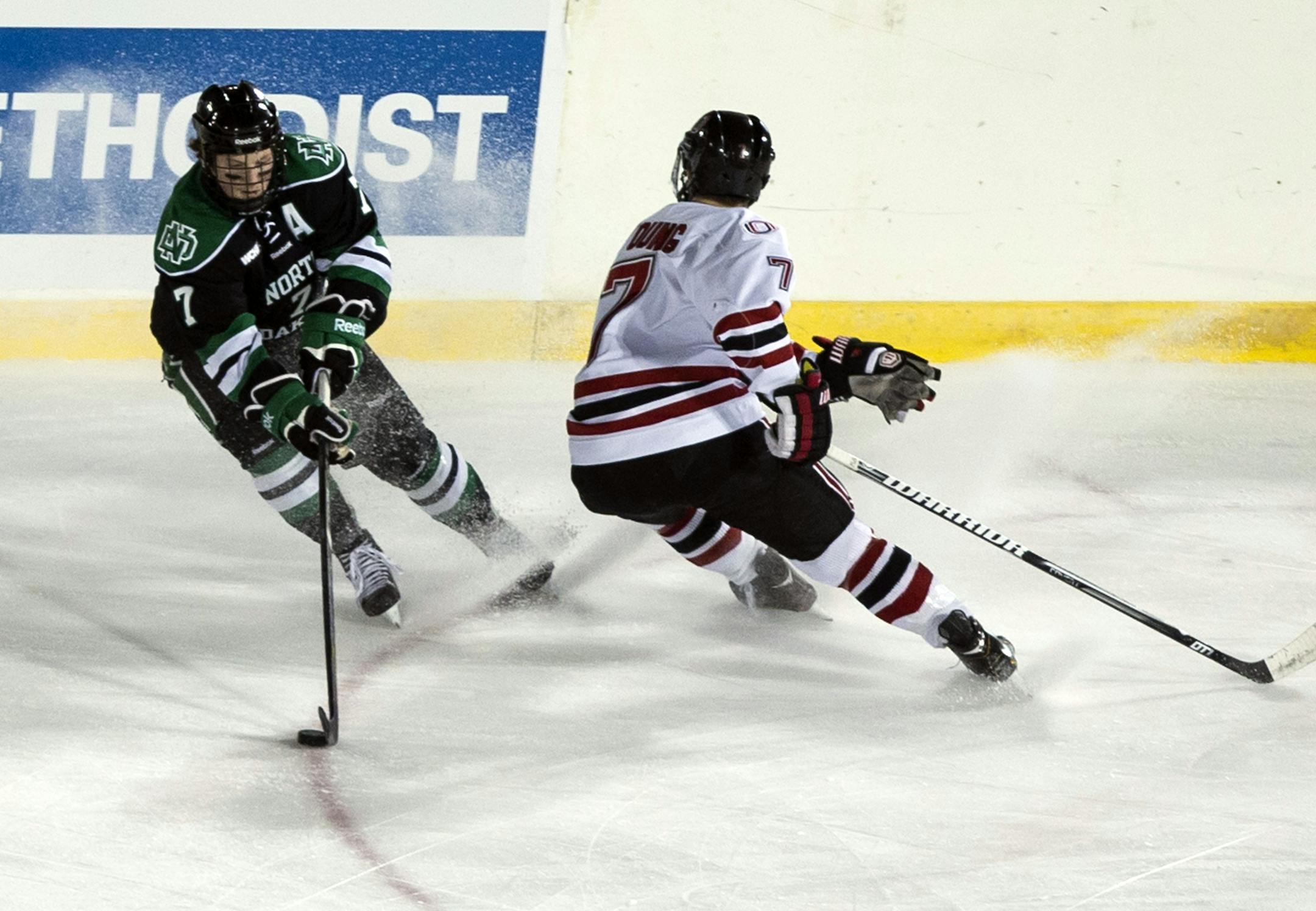 North Dakota's Danny Kristo, left, skates past Nebraska-Omaha's Michael Young in the first period of an NCAA college hockey game held outdoors in Omaha, Neb., Saturday, Feb. 9, 2013. The rink sits between what would be first and third bases at TD Ameritrade Park, the baseball stadium where the College World Series is played each June.(AP Photo/Nati Harnik) ORG XMIT: NENH104
