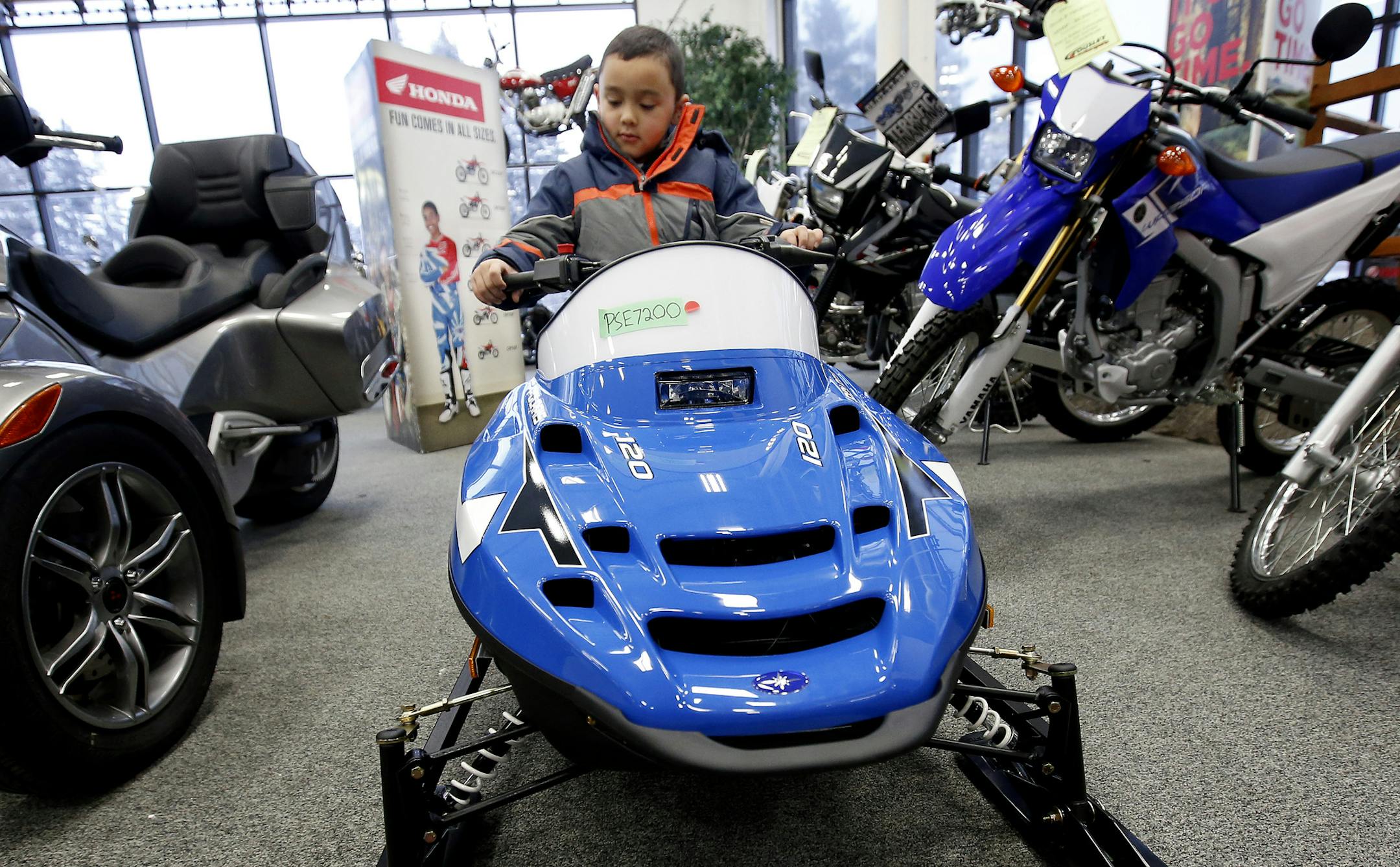 Jordan Asuncion, 7, of Little Canada sat on a snowmobile while looking at off road vehicles with his grandfather Franklin Asuncion at Tousley Motorsports in Vadnais Heights.
