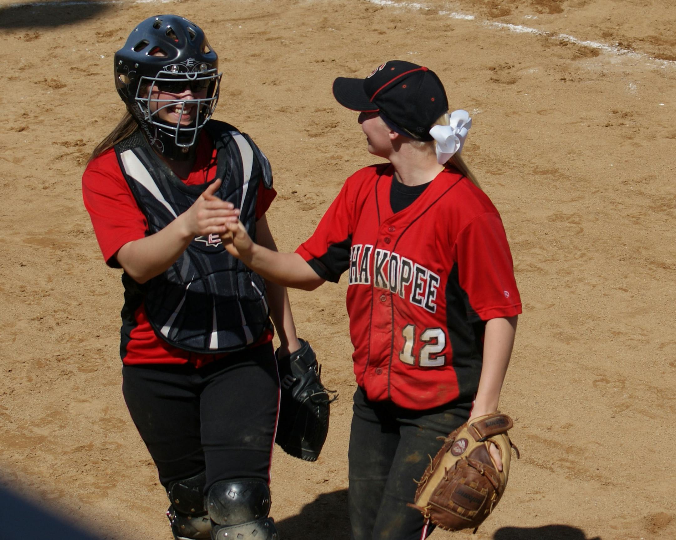 Picture 2: Shakopee pitcher Alexandria Walker (12) gets a high-five from catcher Abbie Annen as first baseman Elizabeth Bruss (4) looks on after the third out of an inning. Walker is the ace of the Sabres‚Äô pitching staff.