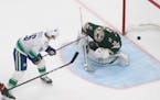 Wild goalie Alex Stalock (32) is scored on by Vancouver Canucks' Antoine Roussel (26) during the third period