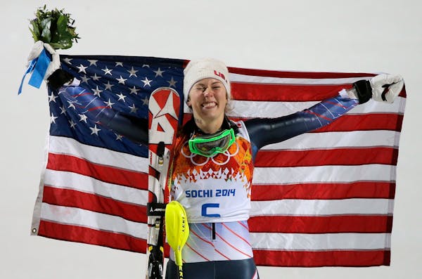 Women's slalom gold medal winner Mikaela Shiffrin of the United States poses for photographers with the American flag at the Sochi 2014 Winter Olympic