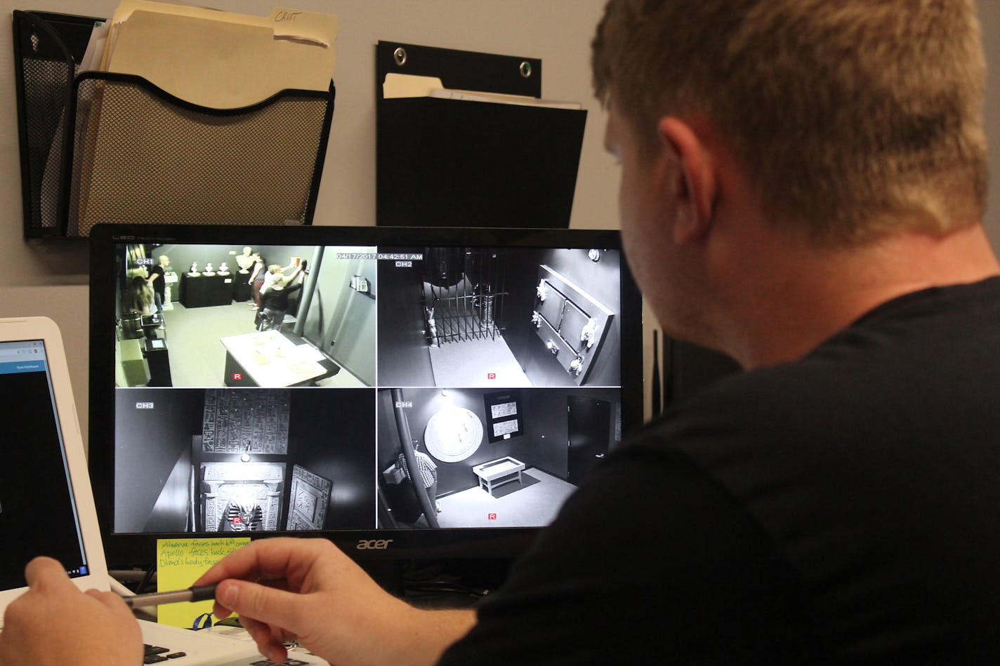 Mission Producer Evan Flolid watches from the control room as a group of employees from the University of Minnesota Medical Center tries to solve a mystery at Escape MSP in St. Paul. Photo by Sharyn Jackson