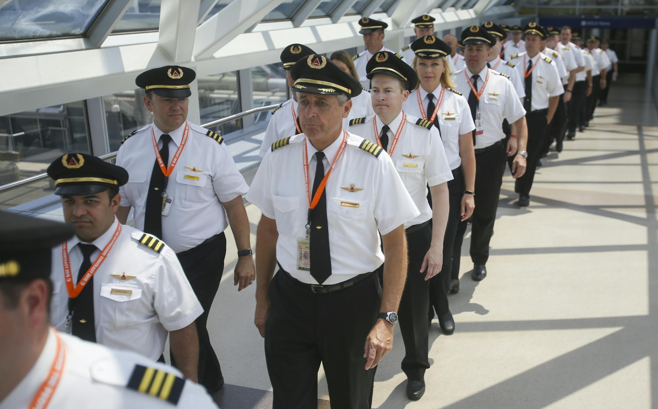 Pilots from Delta Air Lines march through a skyway into the baggage check in.