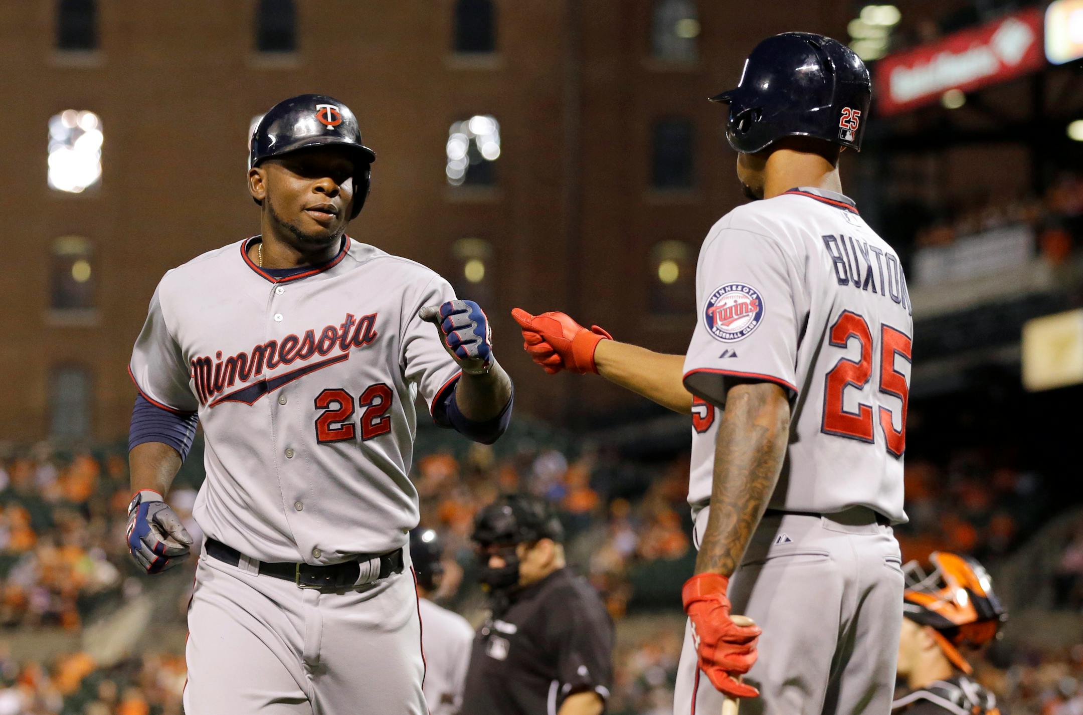 Minnesota Twins' Miguel Sano, left, fist-bumps teammate Byron Buxton after scoring on a bases-loaded walk to Eduardo Nunez during the fourth inning of a baseball game against the Baltimore Orioles, Friday, Aug. 21, 2015, in Baltimore. (AP Photo/Patrick Semansky)