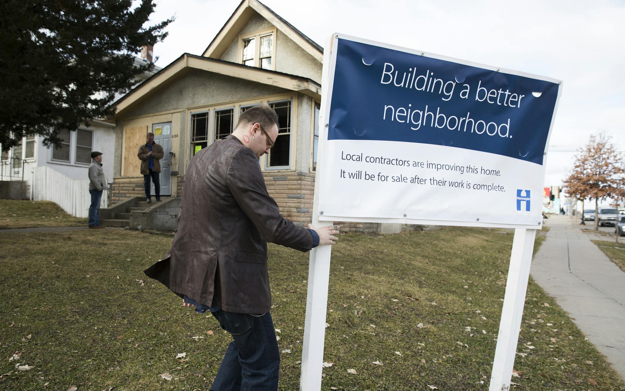 James Sorenson of Hennepin County fixes the sign in front of a home being renovated on Dupont Avenue North in Minneapolis. ] LEILA NAVIDI • leila.navidi@startribune.com BACKGROUND INFORMATION: Tour of homes under renovation in north Minneapolis on Thursday, February 23, 2017. A new Hennepin County pilot program is partnering with small contractor businesses to renovate tax forfeited homes.