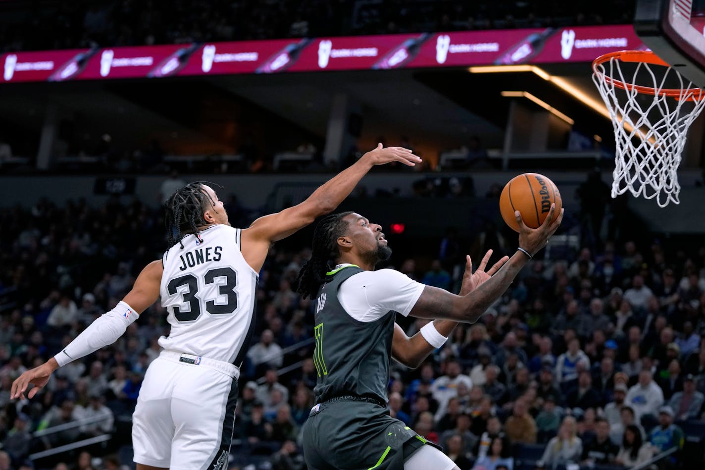 Minnesota Timberwolves center Naz Reid, right, goes up for a shot as San Antonio Spurs guard Tre Jones (33) defends during the first half of an NBA basketball game Wednesday, Dec. 6, 2023, in Minneapolis. (AP Photo/Abbie Parr)