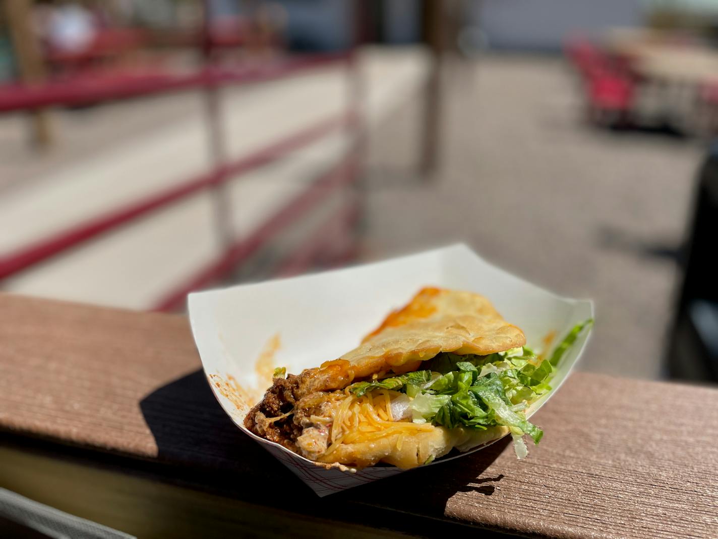 Thick and crispy frybread is wrapped around ground beef, shredded lettuce and shredded cheddar cheese on a fencepost outside the restaurant, inside its patio.