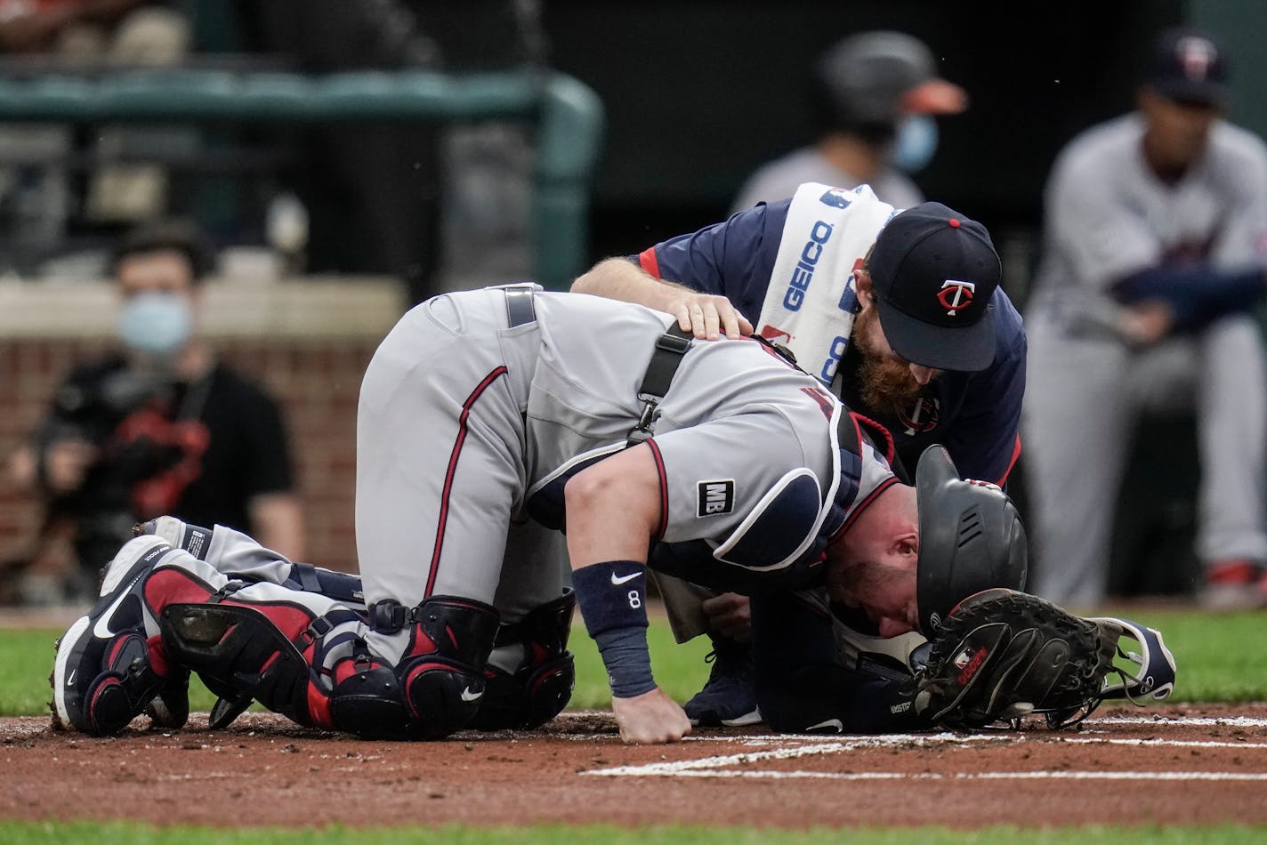 Twins assistant athletic trainer Matt Biancuzzo talks to catcher Mitch Garver after he took a foul ball from Orioles designated hitter Trey Mancini during the first inning