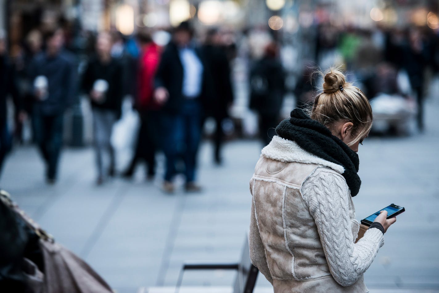 A pedestrian uses her smartphone as she stands on a main shopping street in Vienna, Austria, on Wednesday, Oct. 30, 2013. Telekom Austria AG and local units of Hutchison Whampoa Ltd. and Deutsche Telekom AG tightened their hold on the Alpine republic's mobile-phone market in a spectrum auction that raised 2 billion euros ($2.7 billion). Photographer: Akos Stiller/Bloomberg