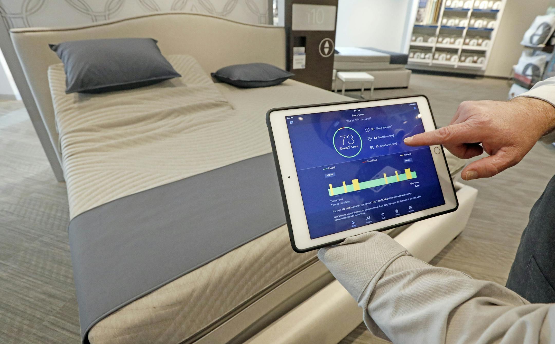 Sleep Number store manager Lee Pulliam demonstrates earlier in the month how the Sleep Number bed technology works. (ROGELIO V. SOLIS/AP)