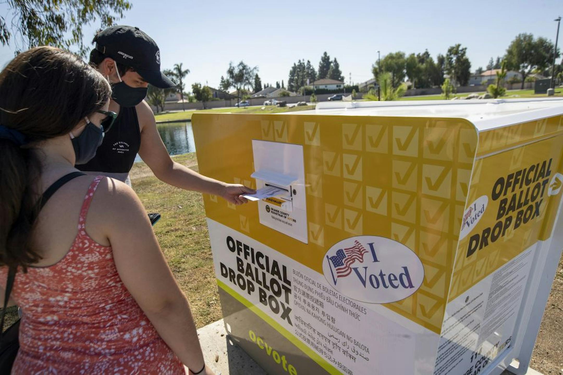 Caitlin Harjes, left, and Angel Santiago, place their ballots inside an official Orange County Registrar of Voters ballot Drop Box for the 2020 Presidential General Election at Carl Thornton Park in Santa Ana, California, on October 13, 2020.