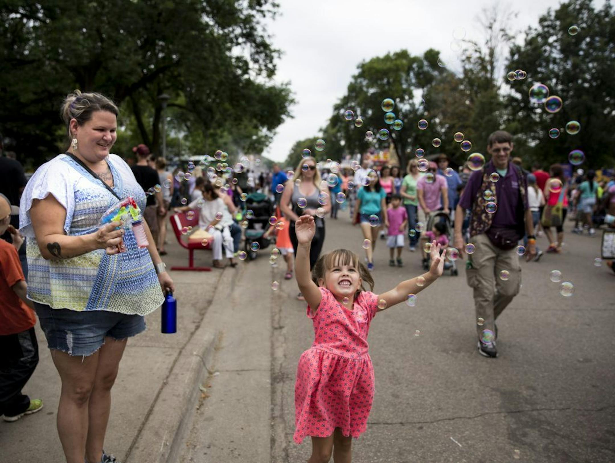 Nicole Morgan, of Burnsville, stood on the curb blowing bubbles onto the road for people walking past to enjoy, a tradition she repeats every year at the fair. Four-year-old Josephine Sande of St. Paul leapt in the air to catch some on the last day of the Minnesota State Fair in Falcon Heights, Minn. on Labor Day, Monday, September 5, 2016. Morgan admits some adults don't love her bubble love but she doesn't care. "I just love the smiles I get," said Morgan.