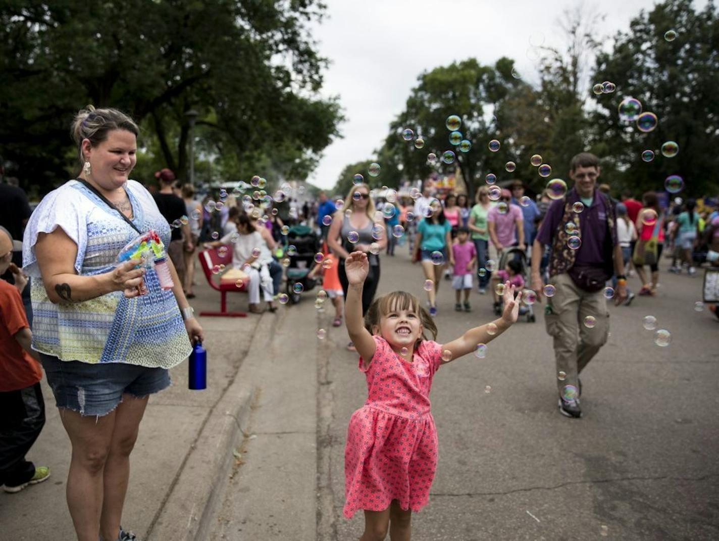 Nicole Morgan, of Burnsville, stood on the curb blowing bubbles onto the road for people walking past to enjoy, a tradition she repeats every year at the fair. Four-year-old Josephine Sande of St. Paul leapt in the air to catch some on the last day of the Minnesota State Fair in Falcon Heights, Minn. on Labor Day, Monday, September 5, 2016. Morgan admits some adults don't love her bubble love but she doesn't care. "I just love the smiles I get," said Morgan.