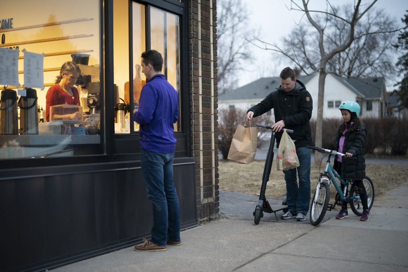 John Vogt and his daughter, Penelope, got ready to ride home with their takeout order Wednesday night while Zoey Brom-Palkowski waited on a customer at Heather's on Chicago Ave. S. in south Minneapolis Wednesday night. The sliding glass walk-up window, intended for summer ice cream orders, has proven very handy since the takeout only policy has been initiated in Minneapolis due to the coronavirus outbreak.