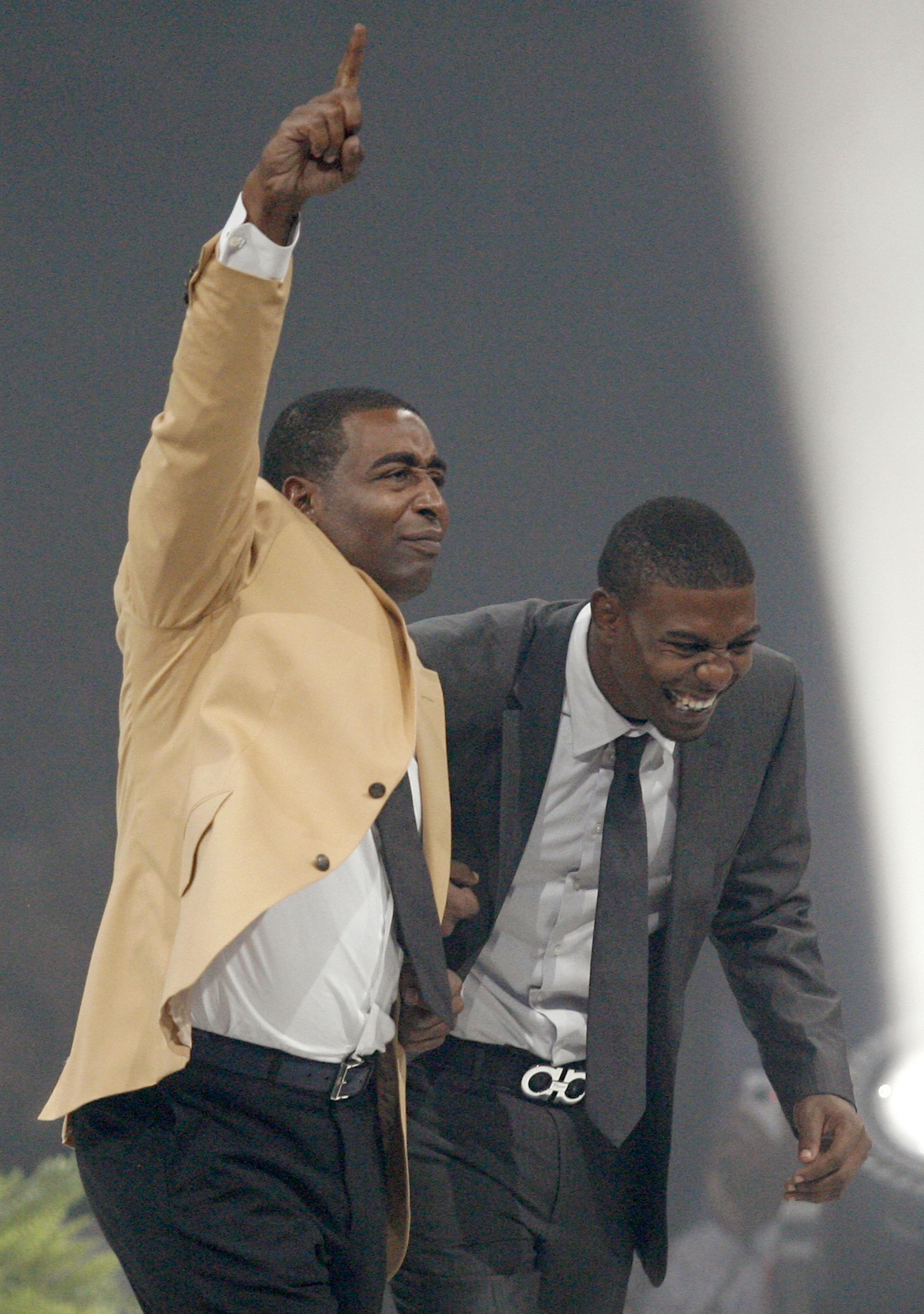 Cris Carter, left, reacts after receiving his symbolic gold jacket from his presenter and son Duron Carter, right, during the Enshrinees' Gold Jacket Dinner at the Canton Memorial Civic Center Friday, Aug. 2, 2013 in Canton, OH. Carter will be enshrined into the Pro Football Hall of Fame Saturday. (AP Photo/The Repository, Scott Heckel)
