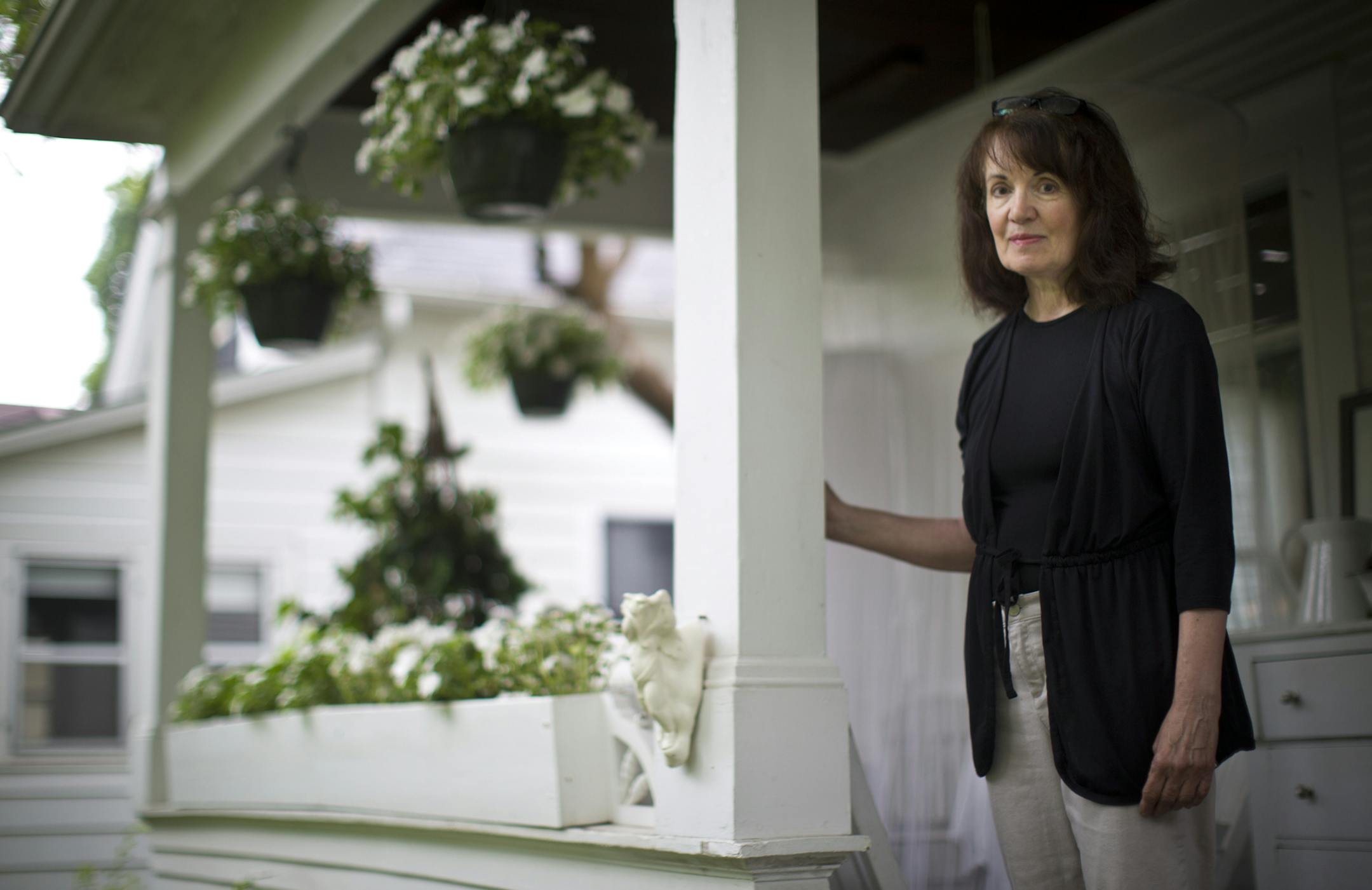 Jeanne Long stood on her front porch where last week several of her hanging baskets were stolen. This is not the first time plants have been stolen from her home. The little statue on the post she is standing on was also stolen last year and she replaced it. She has replaced a few of the stolen baskets and wired them tightly to her porch. She was photographed at home in Minneapolis, Minn., June 12, 2013.] (RENEE JONES SCHNEIDER * reneejones@startribune.com)