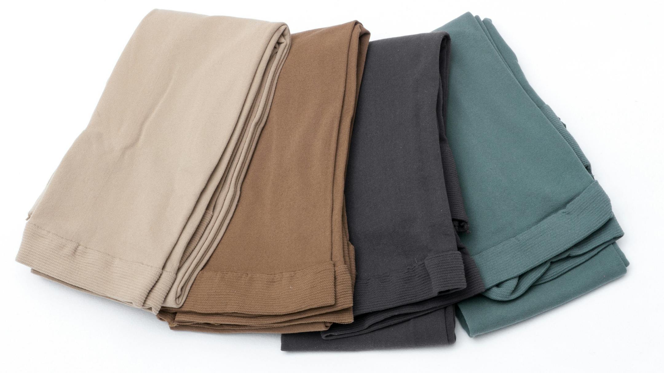 four folded different color leggings, light skin, skin color,dark gray and green. istock