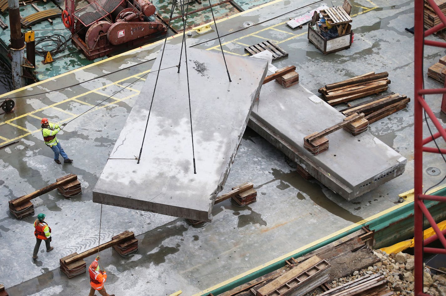 Construction workers help guide a 12 foot by 28 foot roadway panel down from the nearby Franklin Avenue Bridge after the concrete slab was sawed out of the bridge roadway and removed via crane Tuesday, May 10, 2016, in Minneapolis MN. The piece weighed about 25 plus tons or about 13 times what a typical motor vehicle weighs. Construction on the bridge, which began with bridge undercarriage repair in February of 2015, is expected to be completed by June of 2017. The bridge will reopen for traffic