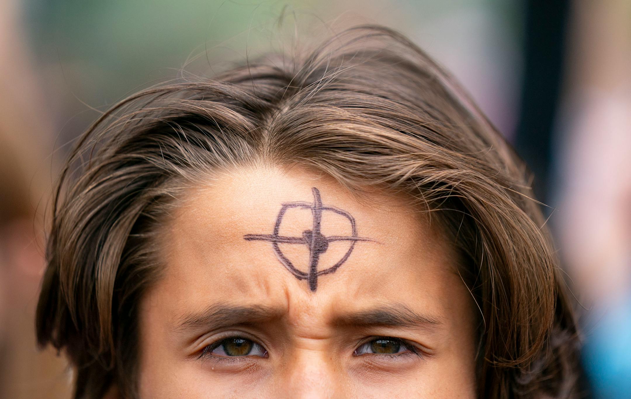 Animikii Skjefte, a sixth-grade student at Justice Page Middle School, drew cross hairs on his forehead during a student walkout and march to protest gun violence .