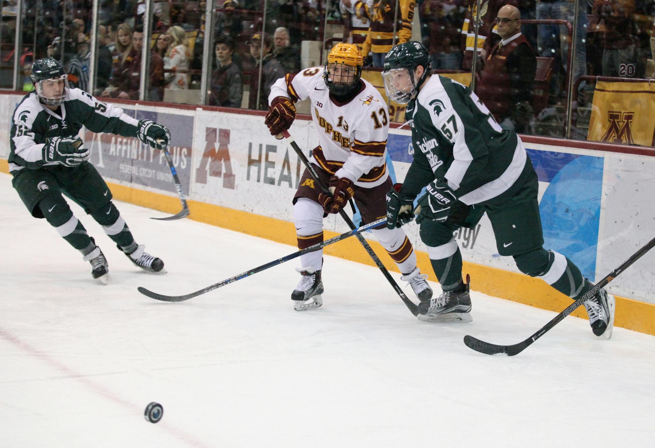 Minnesota Gophers� Taylor Cammarata (13) and Michigan State Spartans� Jerad Rosburg (57) chase the puck in the first period.