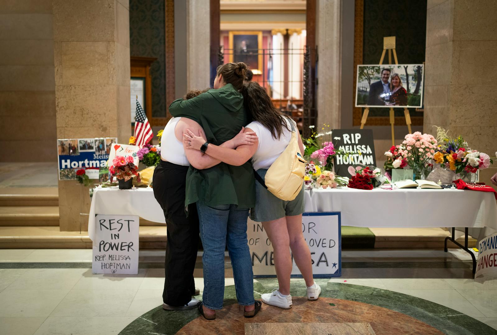 Maria, Katie, and Bridget, who all worked with Minnesota House Democratic leader Melissa Hortman and asked only to use their first names, embrace at a memorial outside the House Chambers for Hortman and her husband Mark Hortman on Monday.