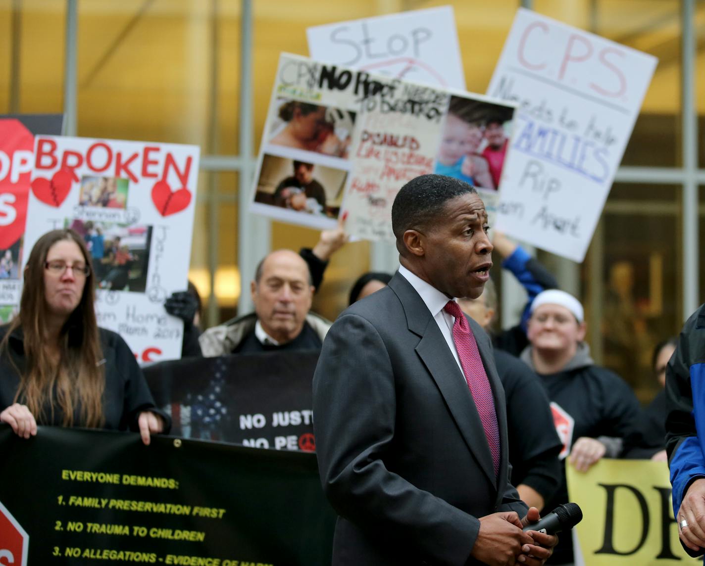 Supporters held signs as Dwight Mitchell talked with with a reporter outside the Federal Building before his lawsuit accusing county and state social service agencies of wrongfully removing children from safe and loving homes and heard Tuesday, Oct. 9, 2018, in St. Paul, MN. His attorneys made opening arguments in Federal Court Tuesday morning in a federal civil rights case in which Mitchell, the plaintiff, alleges that his two children were wrongly removed from his home and placed in foster car