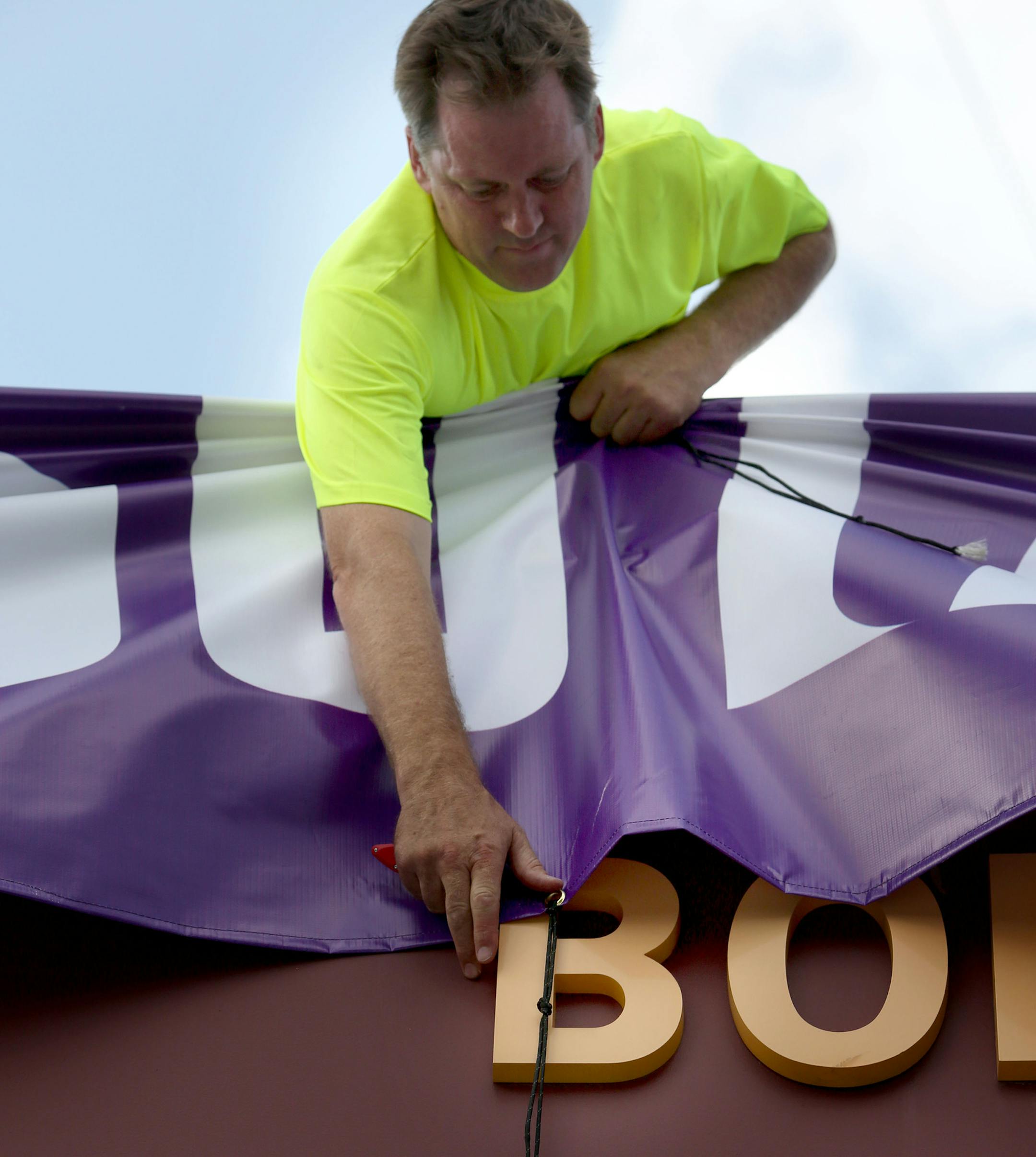 Mike Cofrin fixed one of the banners as they prepare for the Viking game on Friday. ] (KYNDELL HARKNESS/STAR TRIBUNE) kyndell.harkness@startribune.com TCF Bank Stadium changes for Vikings in Minneapolis, Min. Wednesday, August, 6, 2014.
