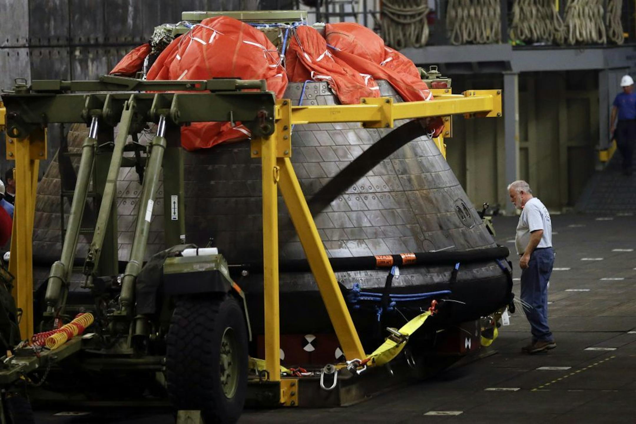 A man looks on as NASA's Orion space capsule is prepared to be unloaded from the USS Anchorage at Naval Base San Diego Monday, Dec. 8, 2014, in San Diego.