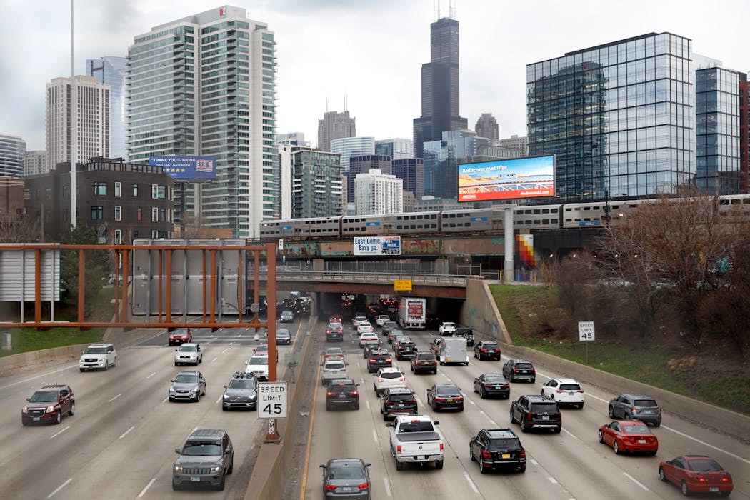 Traffic flows along Interstate 90 as a Metra suburban commuter train moves along an elevated track in Chicago.