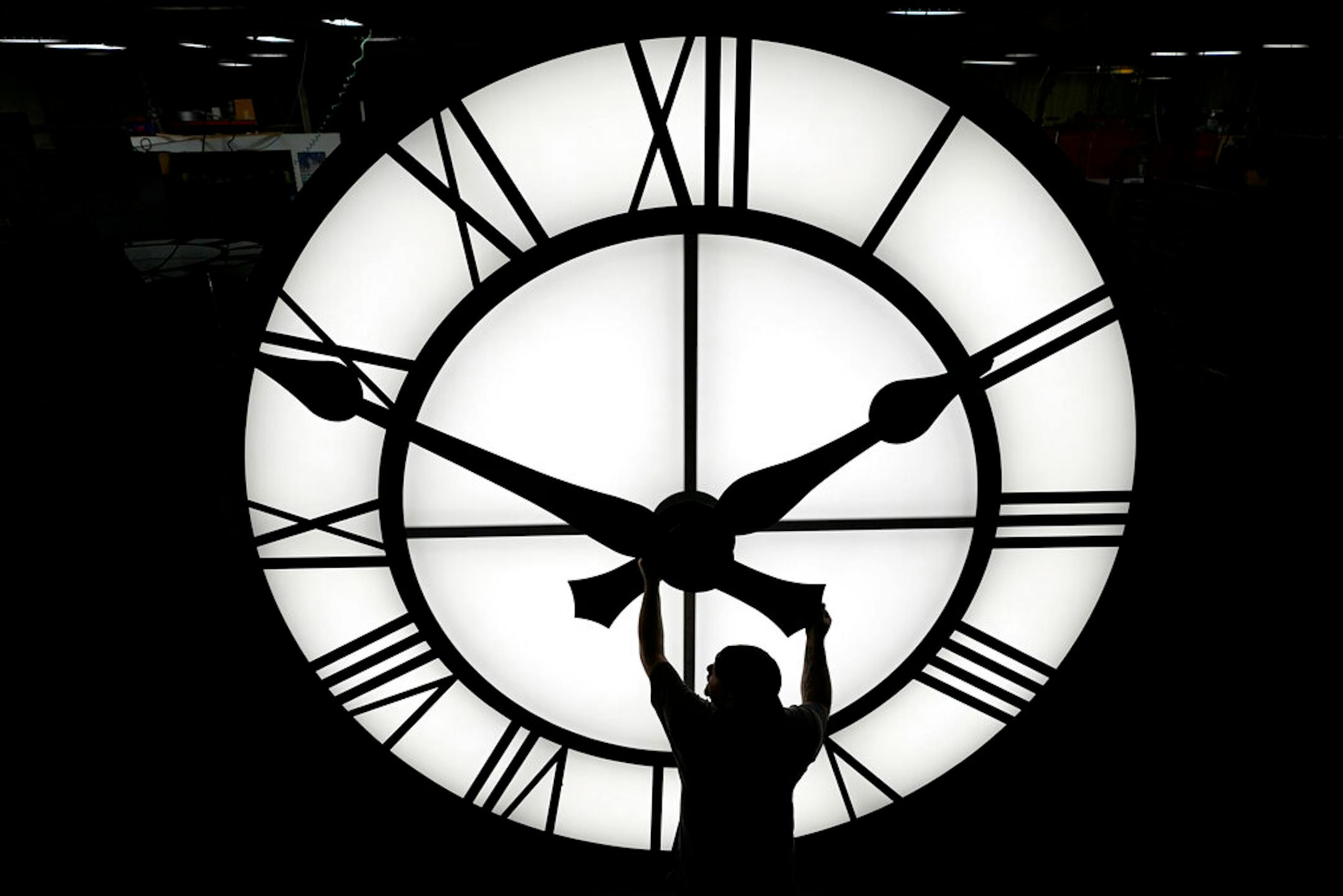 Electric Time technician Dan LaMoore adjusts a clock hand on a 1000-lb., 12-foot diameter clock constructed for a resort in Vietnam, Tuesday, March 9, 2021, in Medfield, Mass. Daylight saving time begins at 2 a.m. local time Sunday, March 14, 2021, when clocks are set ahead one hour. (AP Photo/Elise Amendola)