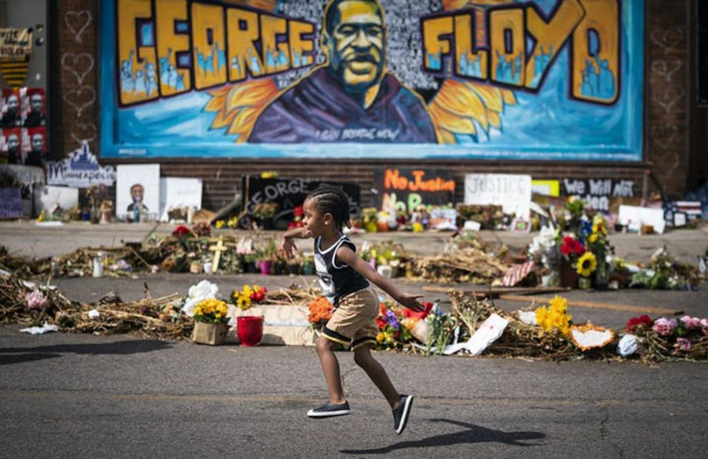 Carter Sims, 3, of Pine Island, Minnesota, runs past a mural at the George Floyd memorial outside Cup Foods in Minneapolis on Thursday, June 25, 2020.