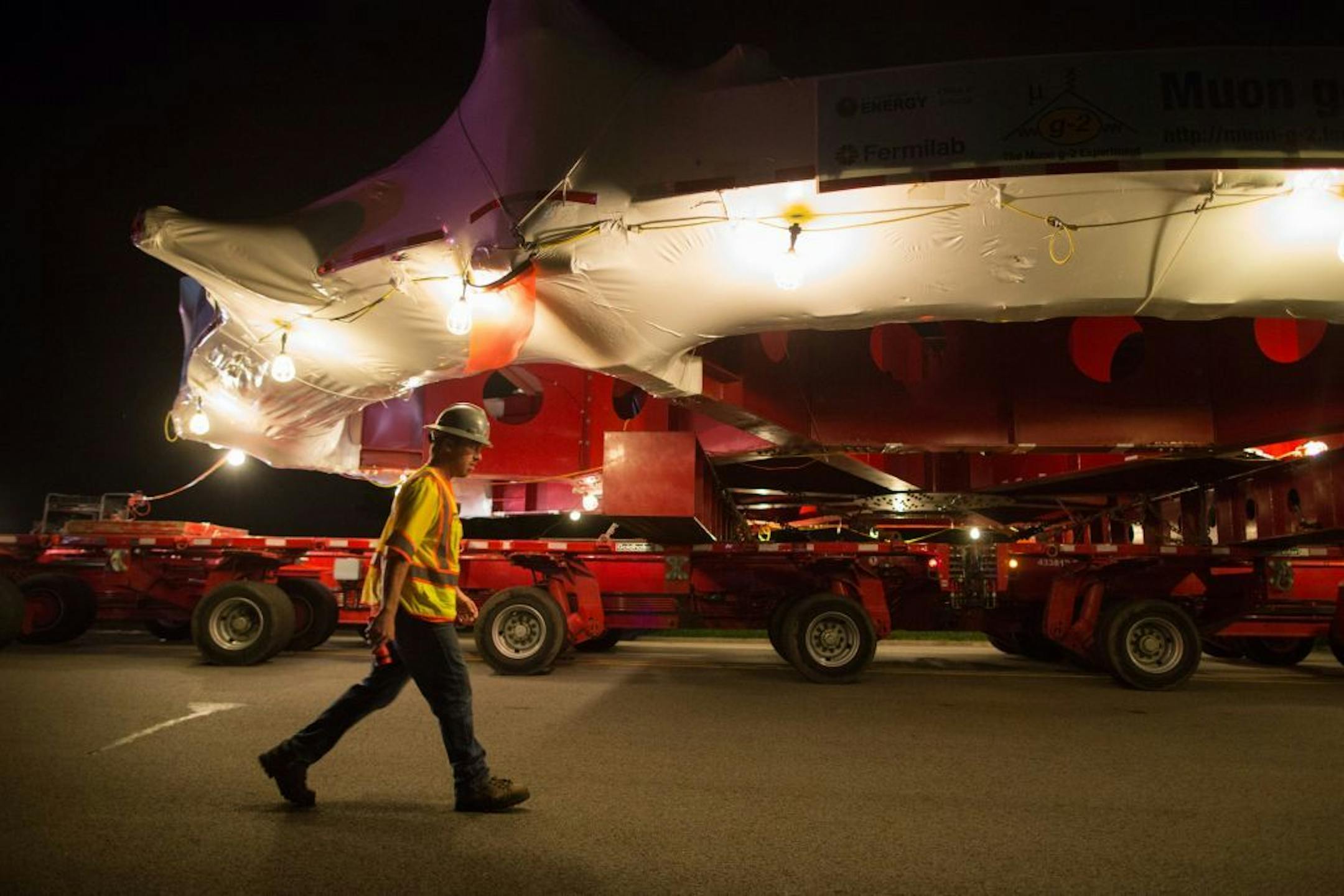A worker walks underneath the electromagnet as it moves down Butterfield Road in Glen Ellyn, Ill., Thursday, July 25, 2013 enroute to its new home outside Chicago on Friday.