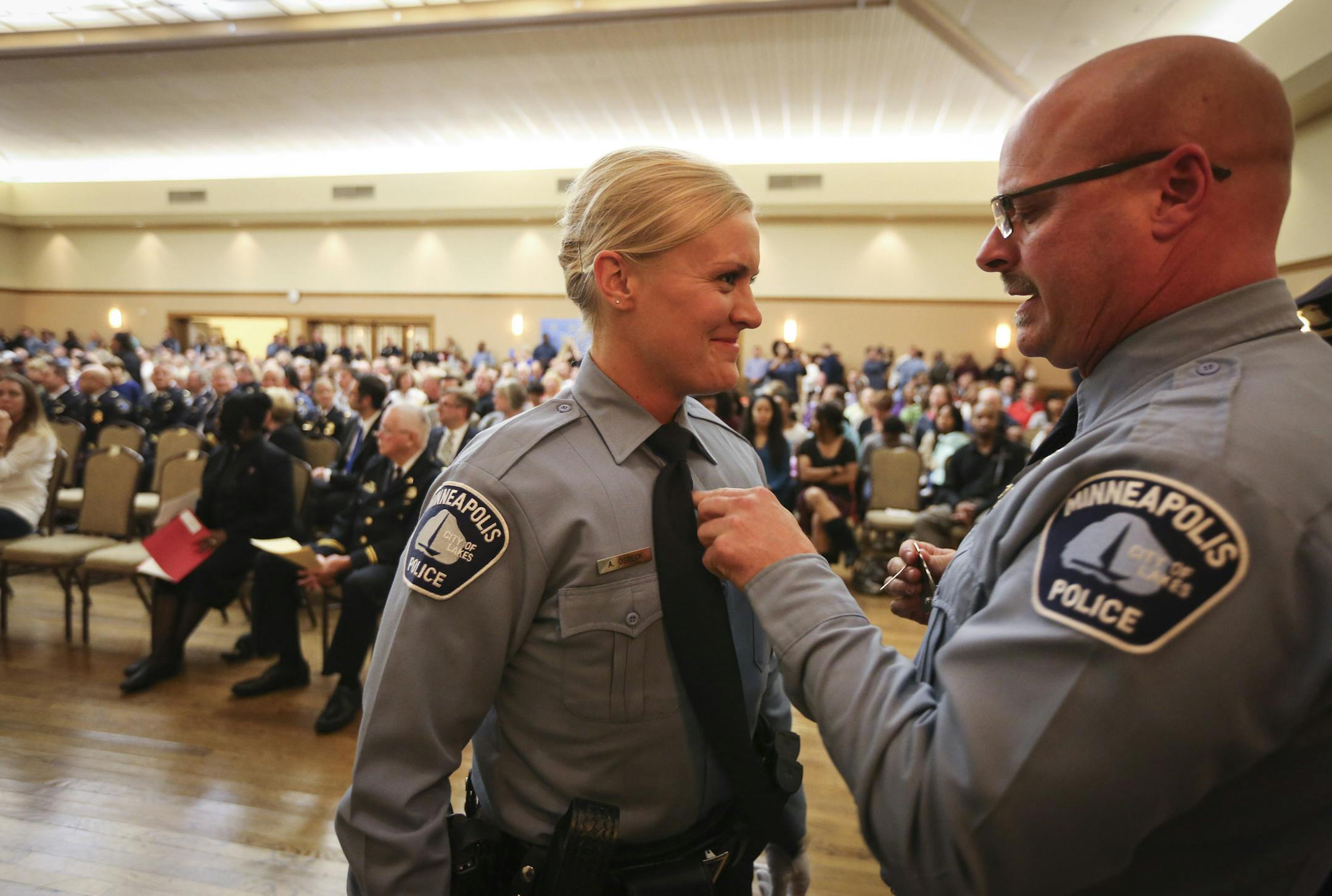 Minneapolis police officer Mike Osbeck pinned a badge on his daughter Angela Osbeck during a Minneapolis Police Department swearing in ceremony in Minneapolis, Minn., on Tuesday, October 20, 2015. Osbeck also has a son who is an police officer. ] RENEE JONES SCHNEIDER • reneejones@startribune.com Following a rigorous 30 week training program at the Minneapolis Police Department’s Academy, 26 recruits are now ready to be sworn-in as Minneapolis Police Officers. Eight of the cadets w