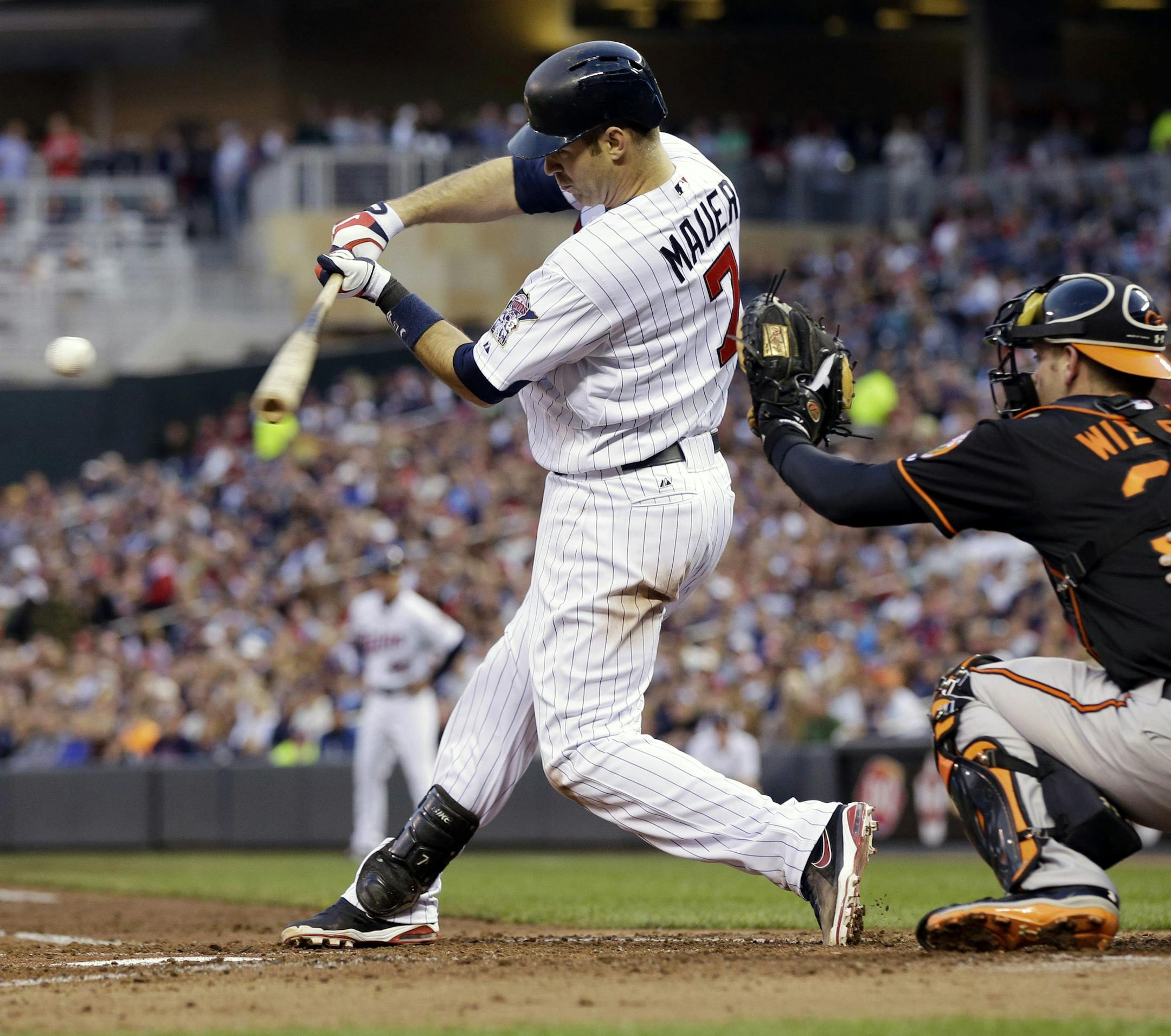 Minnesota Twins' Joe Mauer, left, hits a two-run single off Baltimore Orioles pitcher Jason Hammel in the second inning May 10, 2013.