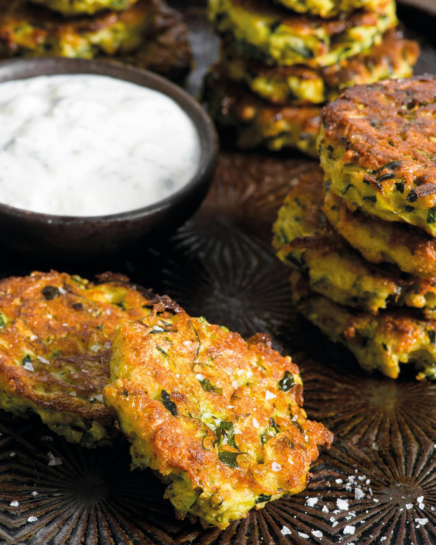 Baked Zucchini Fritters With Feta-Yogurt Sauce, The credit line is as follows: Excerpted from MILK STREET VEGETABLES by Christopher Kimball. Copyright © 2021 by CPK Media, LLC. Photography by Connie Miller of CB Creative, Used with permission of Voracious, an imprint of Little, Brown and Company. New York, NY. All rights reserved.