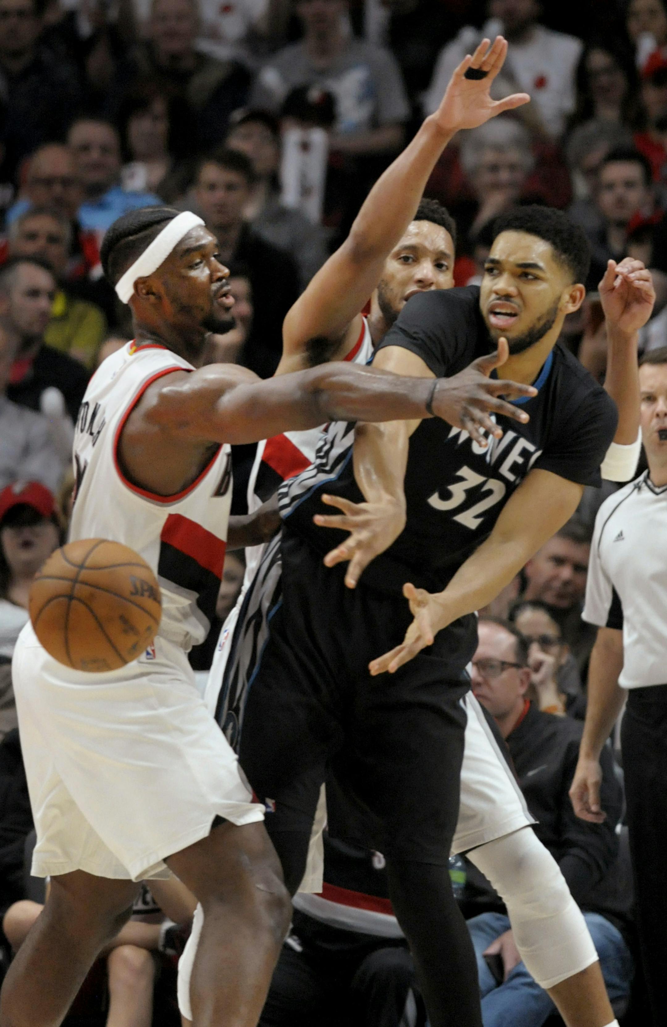 Minnesota Timberwolves center Karl-Anthony Towns passes the ball as Portland Trail Blazers forward Noah Vonleh, left, and guard Evan Turner, rear, defend during the second half of an NBA basketball game in Portland, Ore., Thursday, April 6, 2017. The Blazers won 105-98. (AP Photo/Steve Dykes)