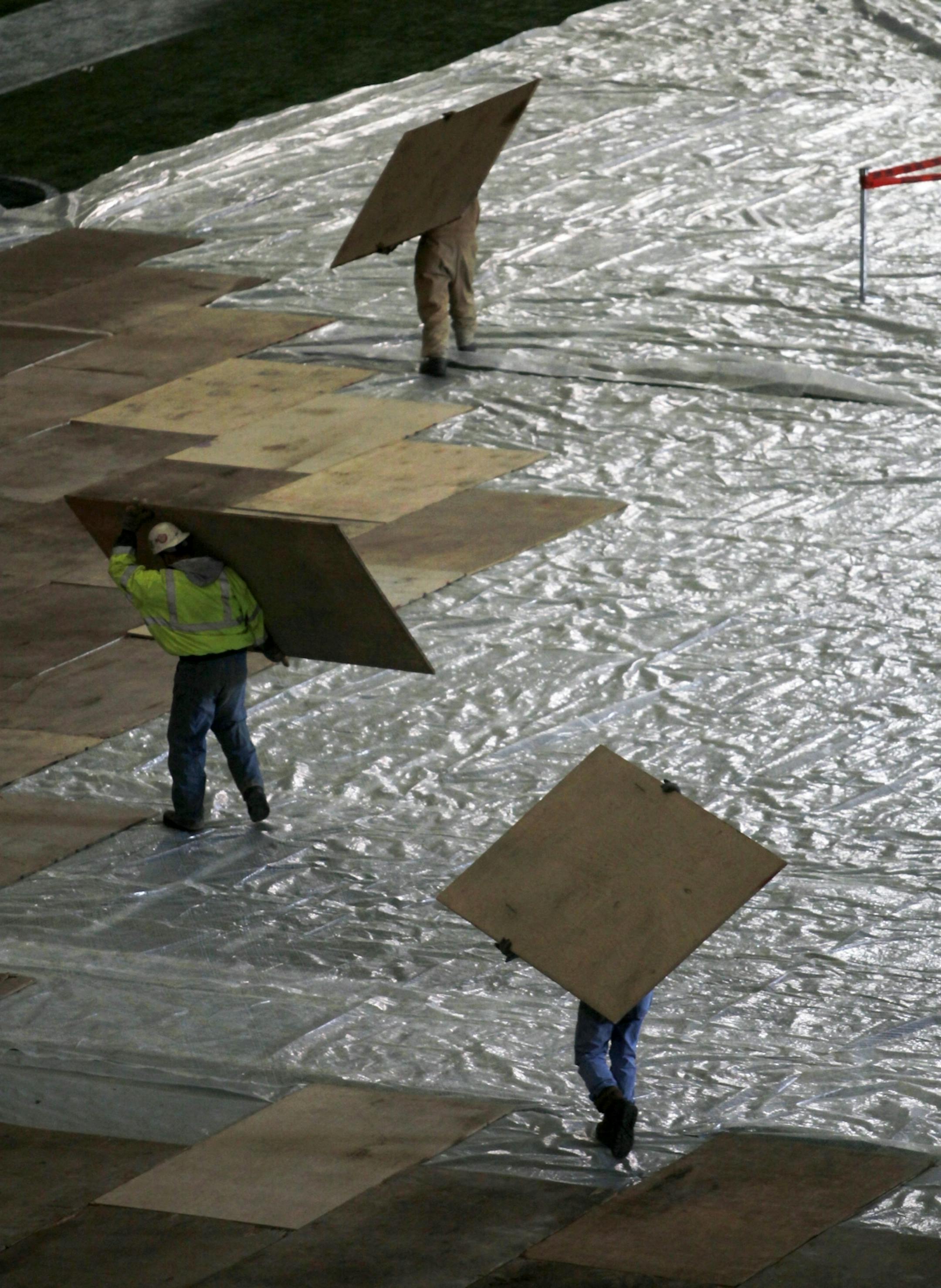 Workers move sheets of plywood onto the floor of Mall of American Field before heavy equipment is brought on for repairs to the roof.