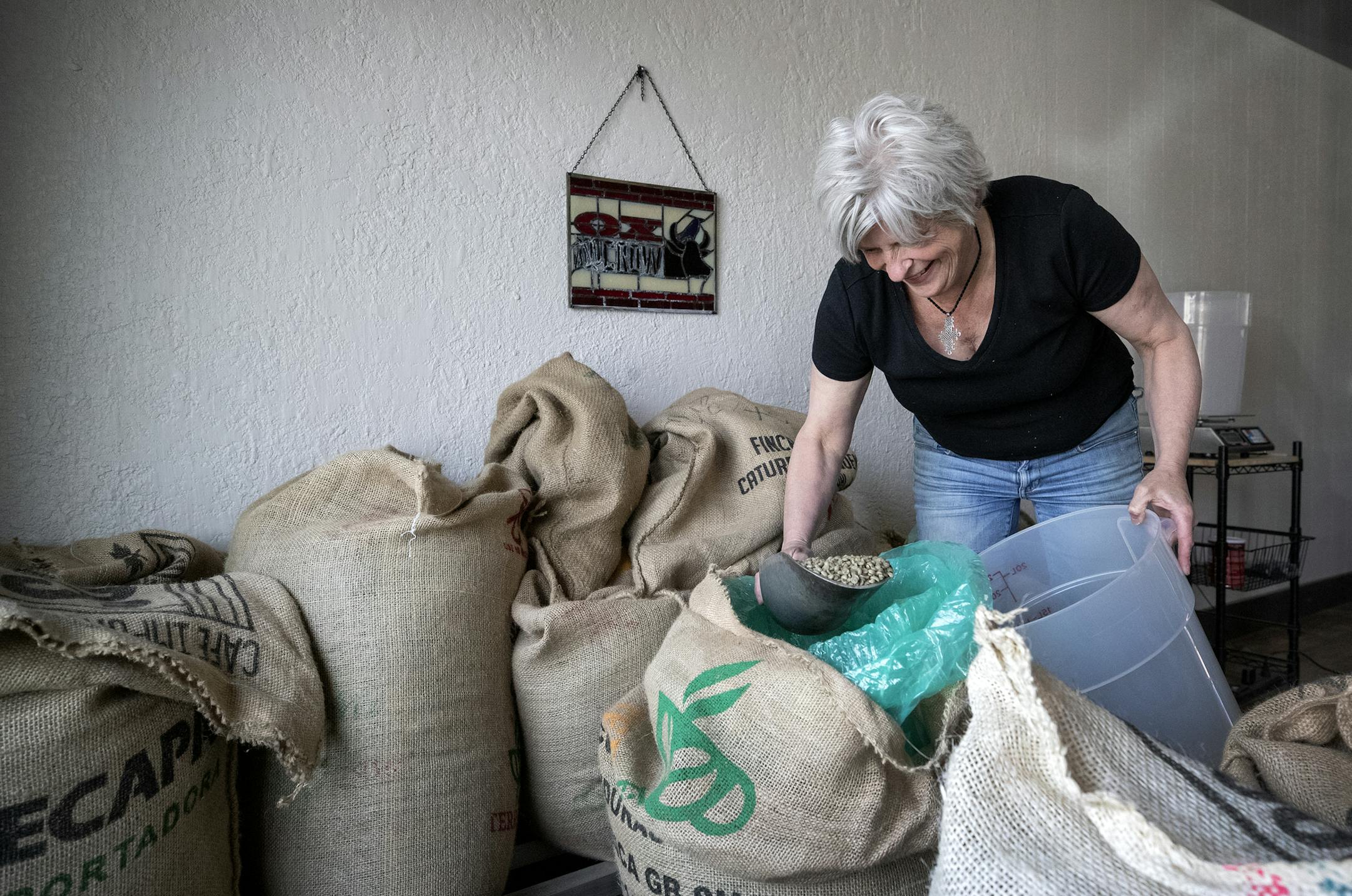 Mara Crombie owner of Ox and Crow demonstrated scooping beans from bags for roasting. ] CARLOS GONZALEZ &#x2022; cgonzalez@startribune.com &#x2013; Lake Elmo, MN &#x2013; May 7, 2020, Ox and Crow Roastery, Two Lake Elmo coffee businesses are teaming up during the pandemic to stay open.