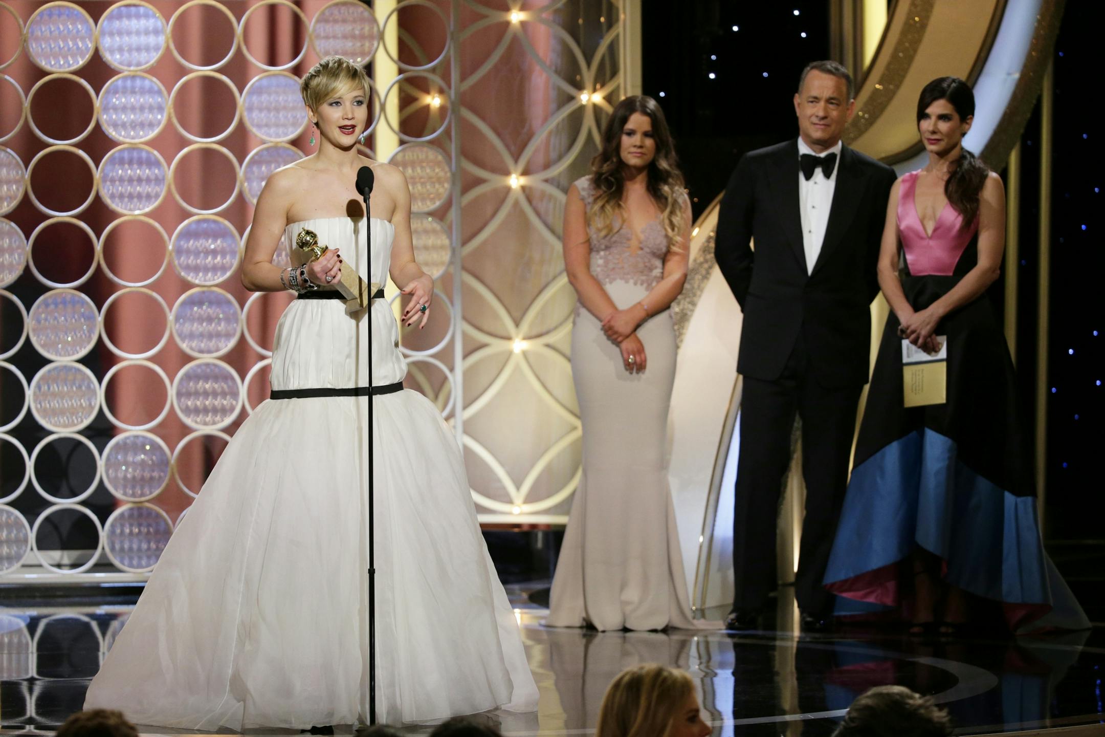 Jennifer Lawrence, left, accepts the award for best supporting actress in a motion picture for her role in "American Hustle," as presenters Sandra Bullock, right, and Tom Hanks, second right, look on.