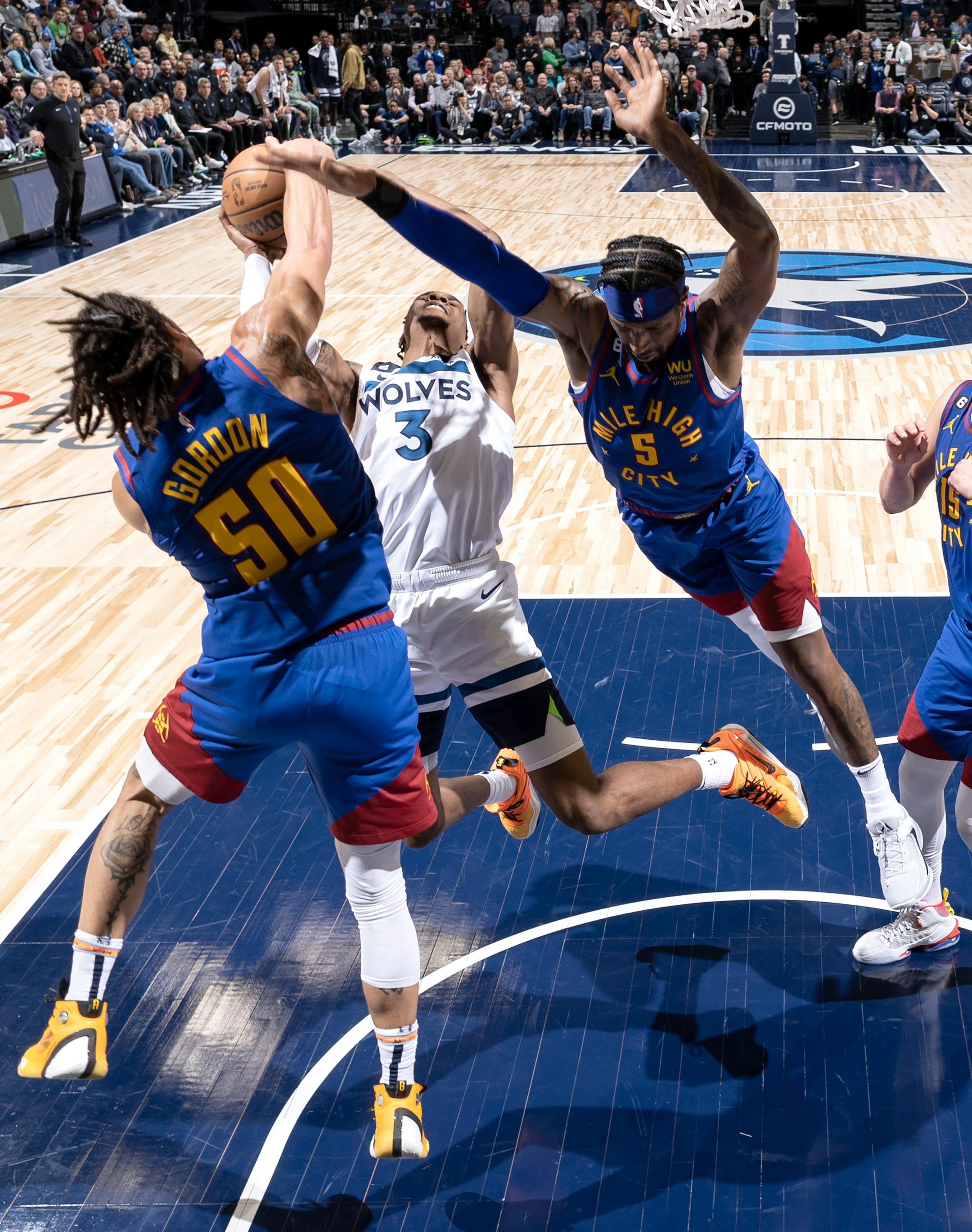 Jaden McDaniels (3) of the Minnesota Timberwolves is defended by Aaron Gordon (50) and defends Kentavious Caldwell-Pope (5) of the Denver Nuggets in the second half.
