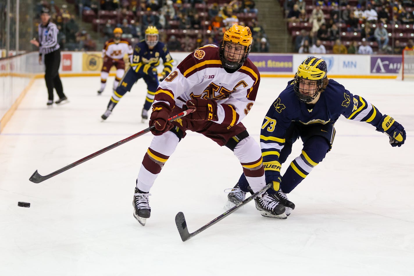 Gophers men's hockey captain Sammy Walker battled for the puck with Michigan defenseman Ethan Edwards on Friday.