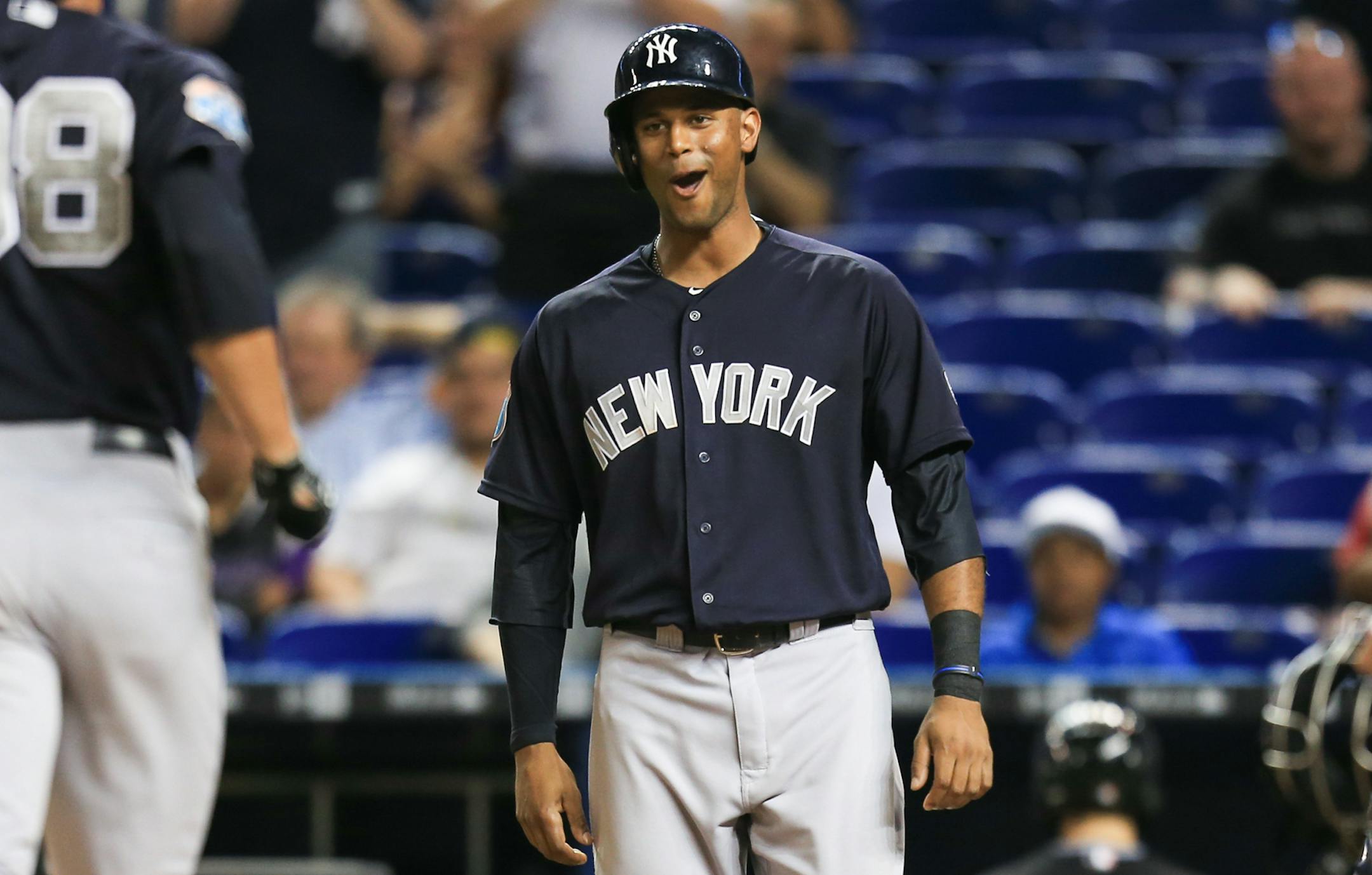 New York Yankees center fielder Aaron Hicks, center, reacts as right fielder Lane Adams (98) crosses home plate after hitting a two-run home run off Miami Marlins relief pitcher A.J. Ramos during the ninth inning of an exhibition baseball game on Friday, April 1, 2016, in Miami. (AP Photo/Rob Foldy)