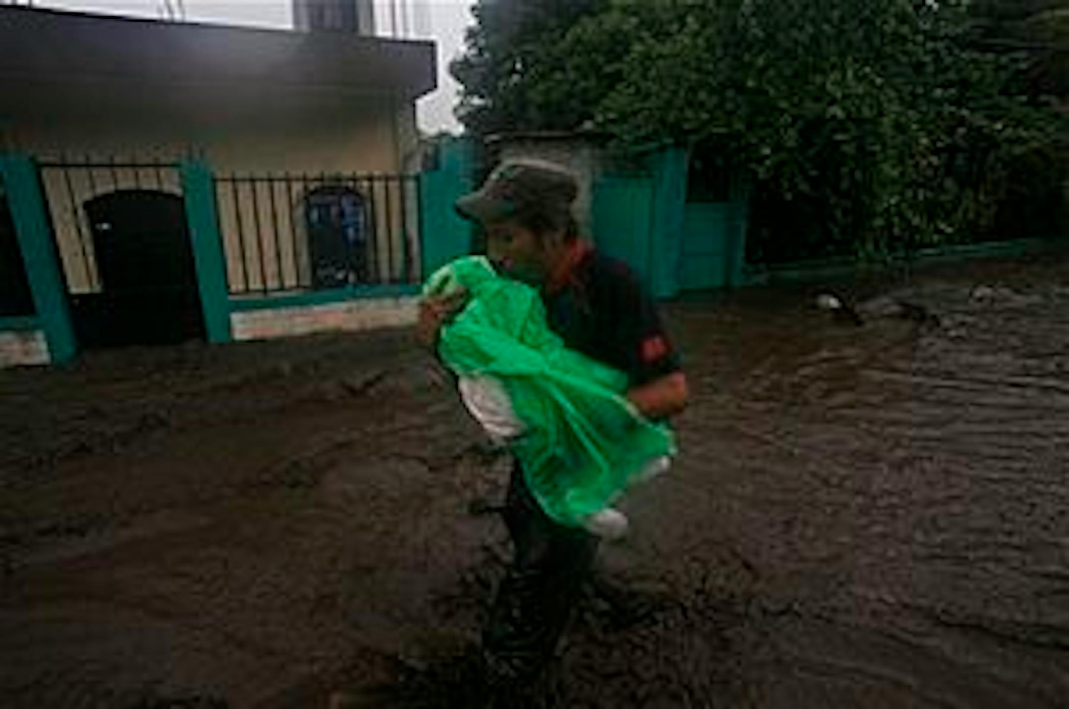 A man carries a child under heavy rains of tropical storm Agatha in Patulul, Guatemala, Saturday, May 29, 2010. (AP Photo/Moises Castillo)
