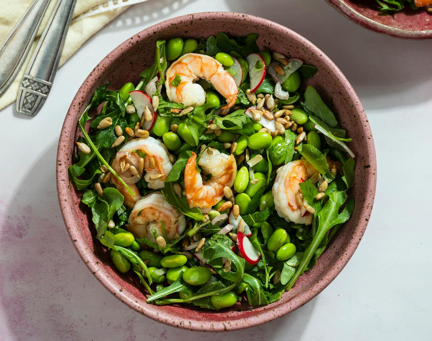 A bowl of Shrimp and Edamame Salad, which also features arugula, radishes, herbs and crunchy sunflower seeds.