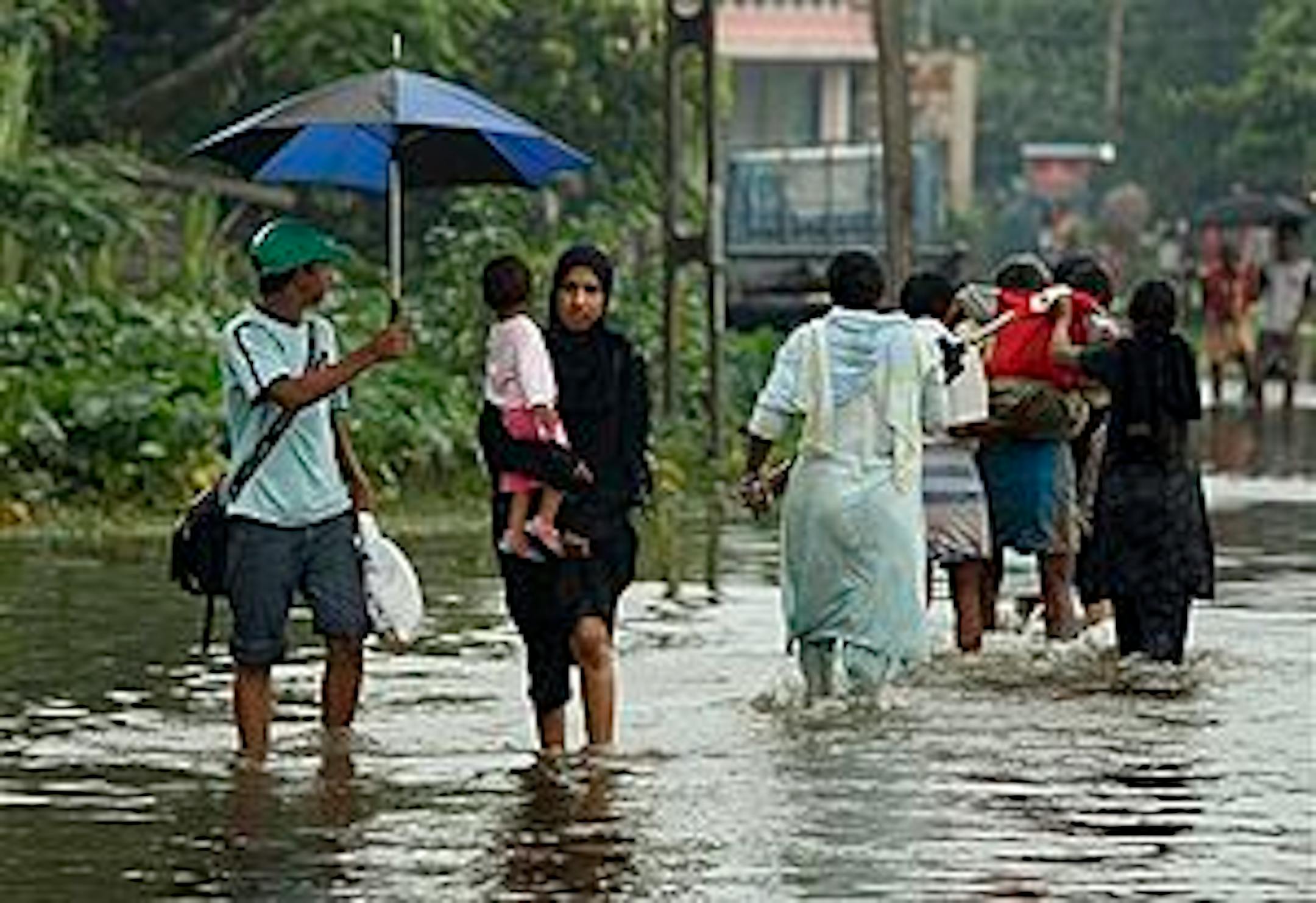 Sri Lankans wade through a submerged road in Colombo, Sri Lanka, Friday, May 21, 2010. Sri Lankan government says that 19 people have died in floods, earth slips and hazards caused by strong winds during a week of heavy rain across the country. (AP Photo/Eranga Jayawardena)
