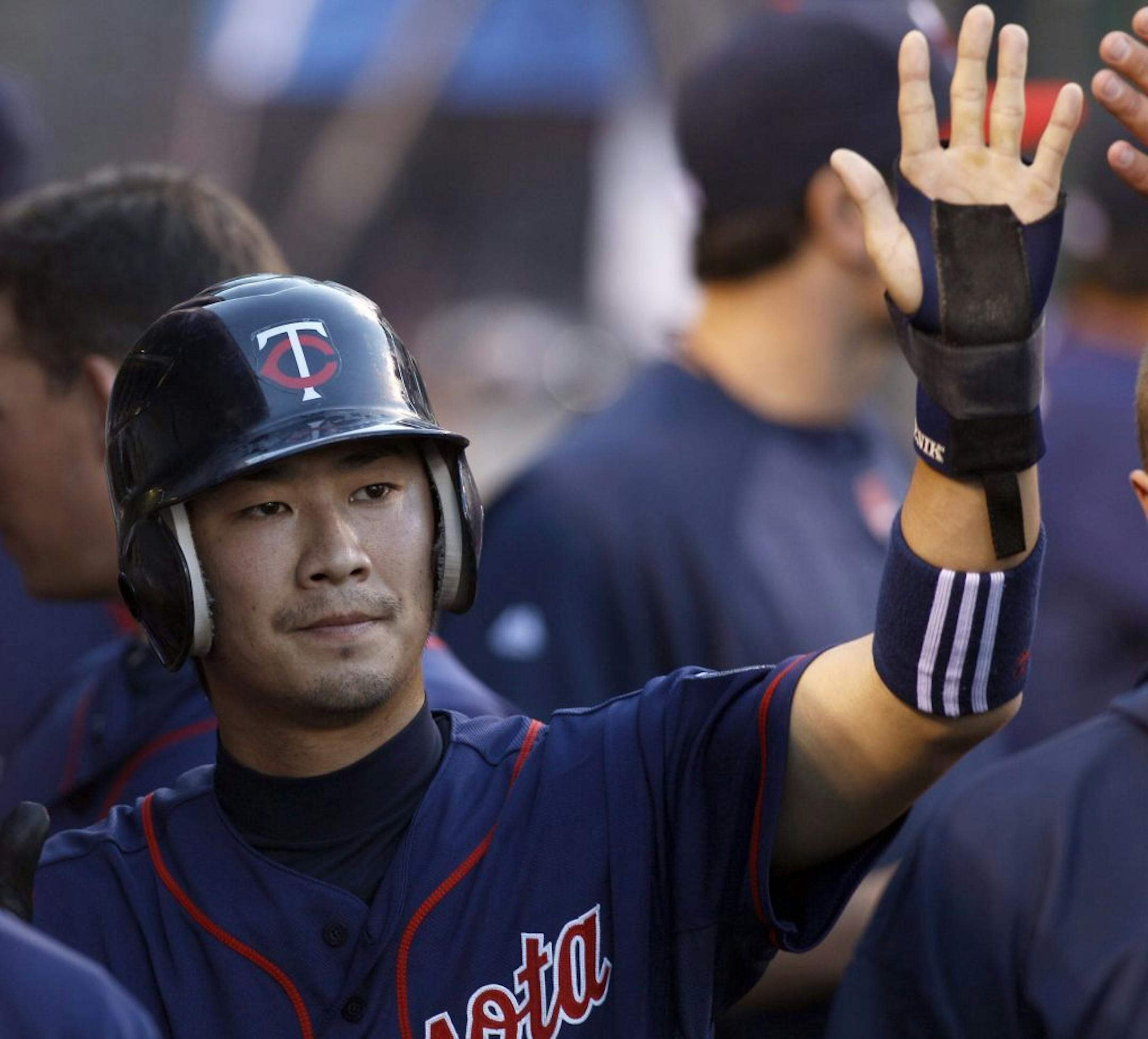 Minnesota Twins' Tsuyoshi Nishioka is congratulated by teammates after scoring on a single by Trevor Plouffe against the Los Angeles Angels during the second inning of their baseball game in Anaheim, Calif., Saturday, Sept. 3, 2011.