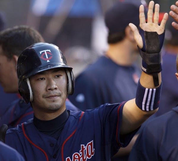 Minnesota Twins' Tsuyoshi Nishioka is congratulated by teammates after scoring on a single by Trevor Plouffe against the Los Angeles Angels during the