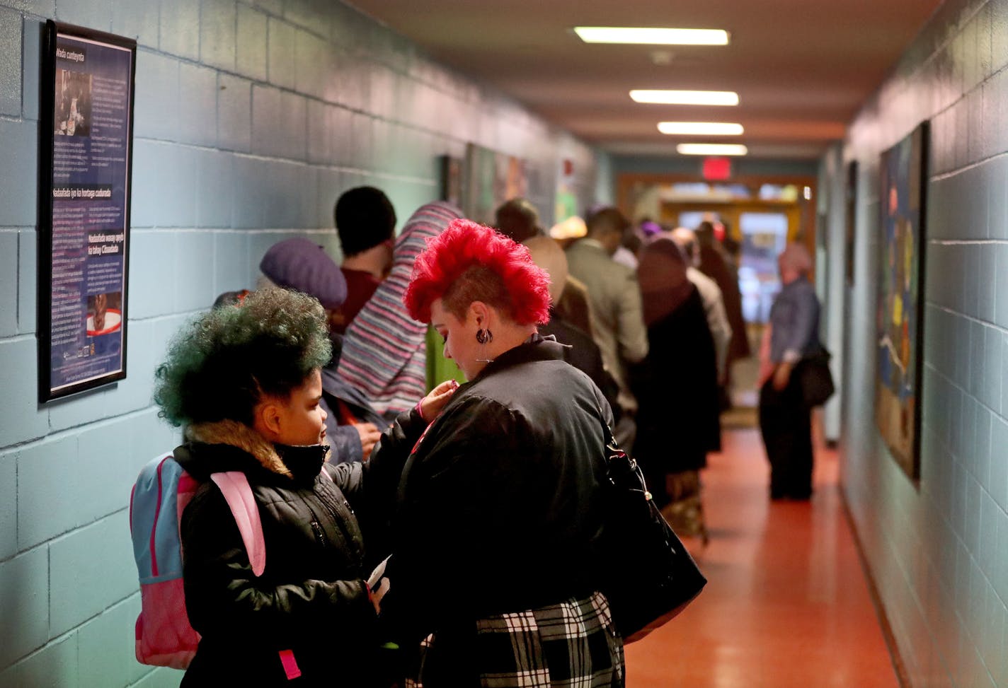 Nicolle Schumacher, middle, of Minneapolis waits in line with her daughter Amaya Williams, 7, before casting her ballot Tuesday, Nov. 8, 2016, at Brian Coyle Center in Minneapolis, MN. Schumacher wanted to teach her daughter about the voting process. "You were in my tummy last time I voted," recalled Williams, who said she voted for President Barack Obama in 2008.