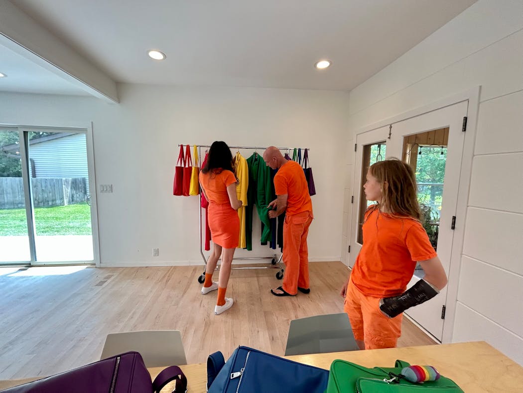 Claire and Darren DeBerg look over some garments from their Monochrome brand in their home. Eleven-year-old Harold is in the foreground beside the family’s backpacks.