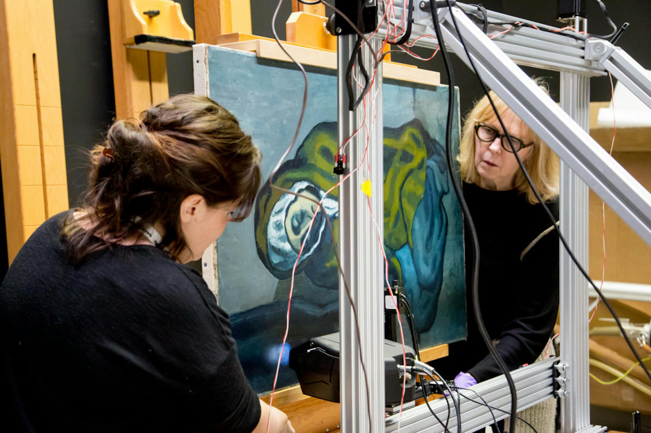 In a photo provided by the Art Gallery of Ontario, Emeline Pouyet, left, of Northwestern University, and Sandra Webster-Cook of the Art Gallery of Ontario using an X-ray fluorescence instrument to scan Picasso’s “La Miséreuse accroupie,” a 1902 painting from Picasso's "Blue Period." Scientists used a variety of tools originally developed for medicine, manufacturing and geology to discover hidden details in the artist’s paintings and sculptures. (Art Gallery of On
